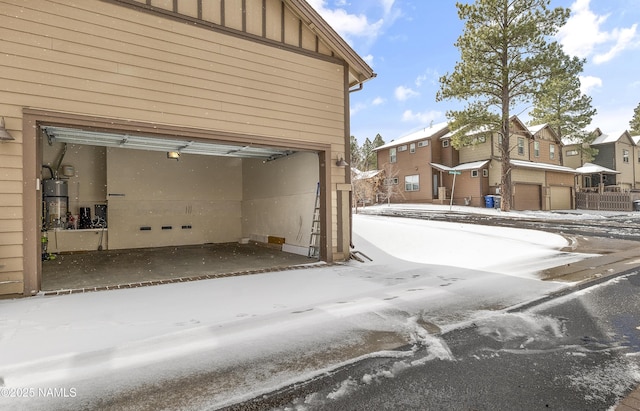 snow covered garage featuring secured water heater and a residential view