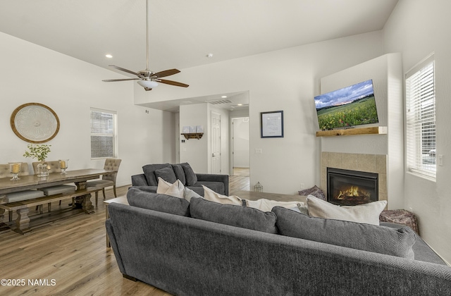 living area with recessed lighting, visible vents, a ceiling fan, light wood-style floors, and a tiled fireplace