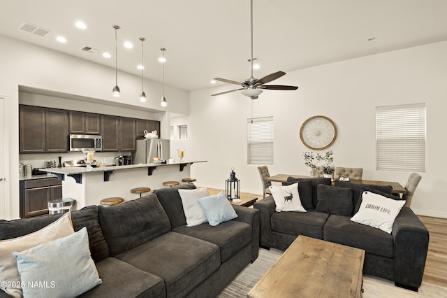 living room featuring a ceiling fan, light wood-type flooring, visible vents, and recessed lighting