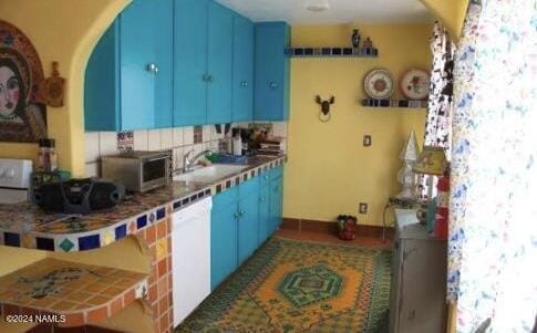 kitchen with sink, dishwasher, and blue cabinetry