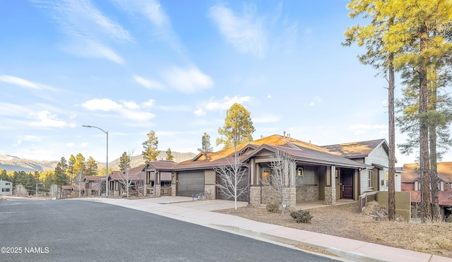 view of front of house featuring stone siding, an attached garage, and concrete driveway