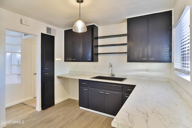 1009 Bales Ave, Winslow, AZ 86047 - kitchen with a sink, open shelves, hanging light fixtures, light stone counters, and baseboards