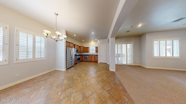 kitchen featuring a notable chandelier, decorative light fixtures, appliances with stainless steel finishes, and light carpet