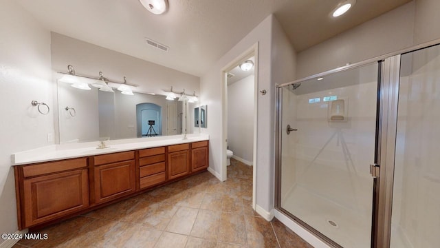 bathroom with vanity, toilet, and a shower with shower door