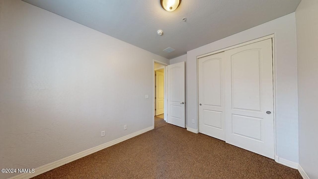 unfurnished bedroom with a closet and dark carpet