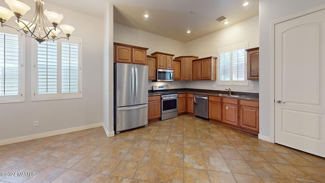 kitchen featuring sink, stainless steel appliances, an inviting chandelier, and pendant lighting