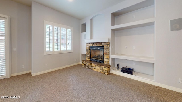 carpeted living room with built in shelves and a stone fireplace