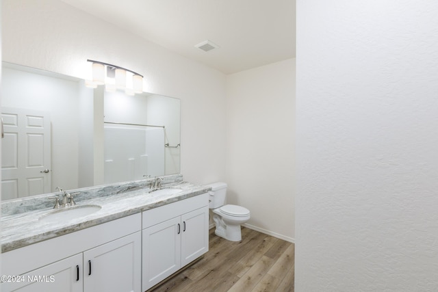 bathroom featuring hardwood / wood-style floors, toilet, walk in shower, and vanity