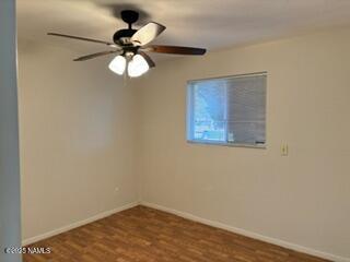 empty room with ceiling fan, baseboards, and wood finished floors