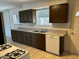 kitchen featuring white appliances, light countertops, a sink, and dark brown cabinets