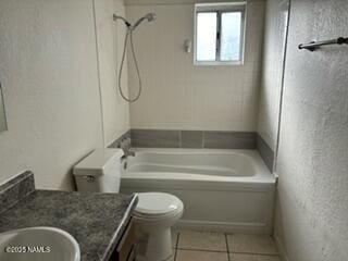 full bathroom with a textured wall, toilet, vanity,  shower combination, and tile patterned floors