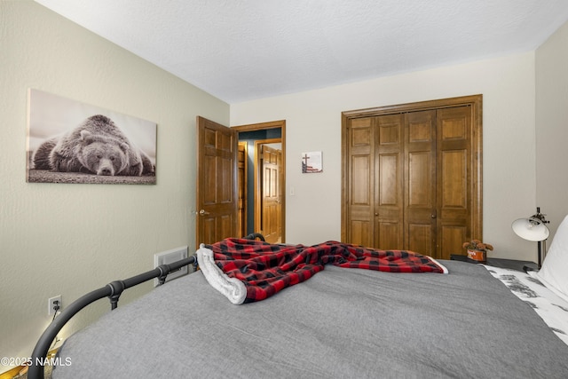 bedroom featuring a textured ceiling, visible vents, and a closet