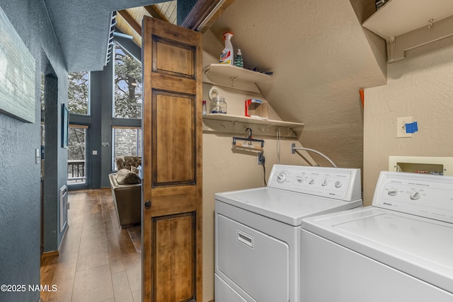 washroom featuring a textured wall, laundry area, wood-type flooring, and washing machine and clothes dryer