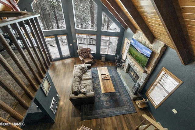 living room with a high ceiling, wood finished floors, and a stone fireplace