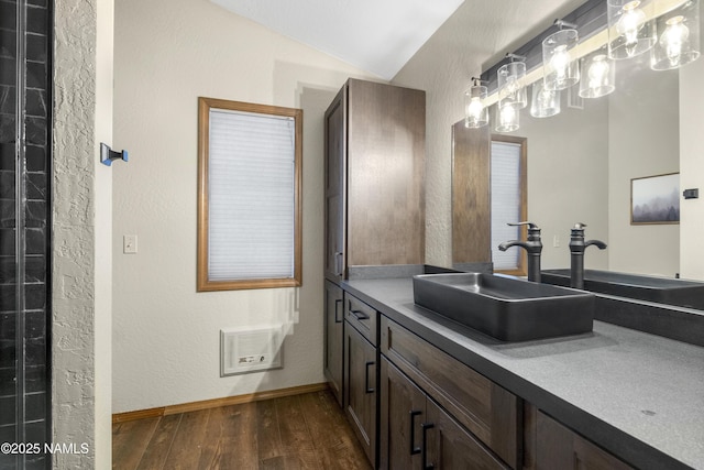 bathroom featuring wood finished floors, vanity, visible vents, vaulted ceiling, and baseboards