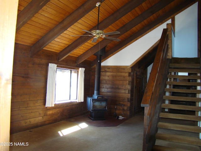 unfurnished living room featuring wood ceiling, lofted ceiling with beams, a wood stove, and wood walls