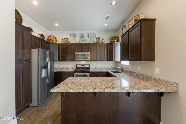 3223 S Beringer Ln, Flagstaff, AZ 86005 - kitchen with appliances with stainless steel finishes, dark brown cabinets, a peninsula, dark wood-style floors, and recessed lighting