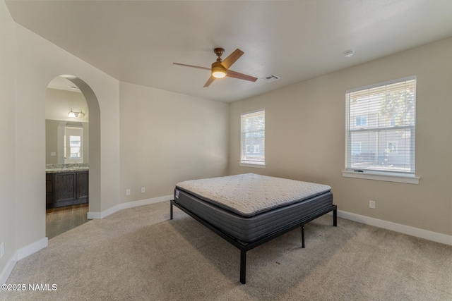 3223 S Beringer Ln, Flagstaff, AZ 86005 - bedroom with light carpet, arched walkways, connected bathroom, and ceiling fan