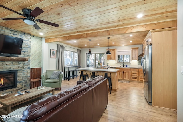 living room featuring wooden ceiling, light wood-type flooring, sink, and a fireplace