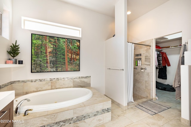 full bathroom with vanity, a walk in closet, a bath, and a shower stall