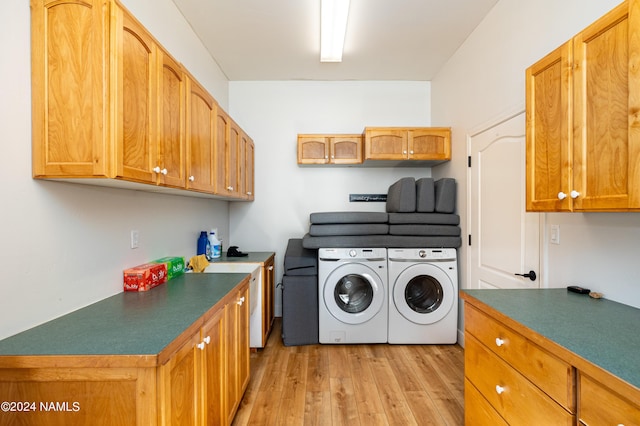 washroom featuring washer and dryer, cabinet space, and light wood finished floors