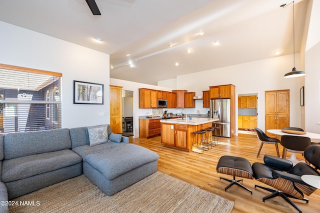 living area with light wood-style floors, ceiling fan, high vaulted ceiling, and beamed ceiling