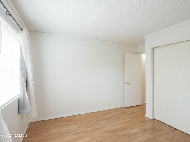 2401 N W St Unit 107, Flagstaff, AZ 86004 - unfurnished bedroom featuring ornamental molding, light wood finished floors, a textured ceiling, and a closet