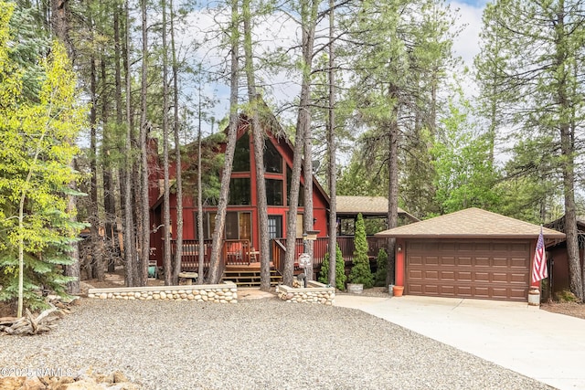 a-frame style home featuring a detached garage, a shingled roof, an outdoor structure, and a wooden deck