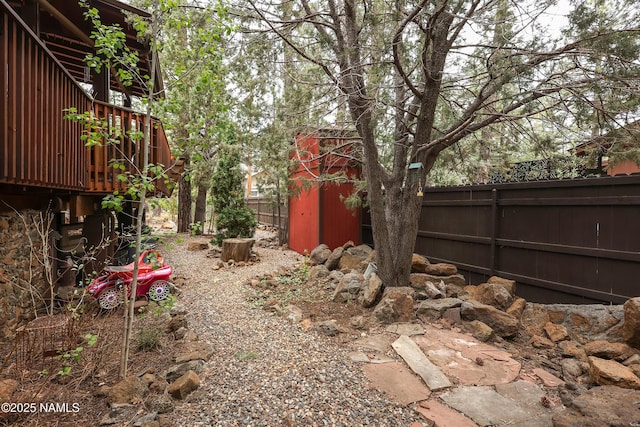 view of yard with fence, an outdoor structure, and a storage unit