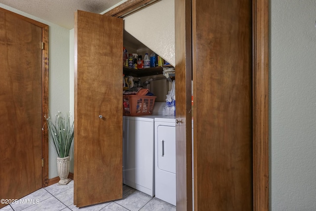 laundry area featuring independent washer and dryer, light tile patterned floors, and a textured ceiling