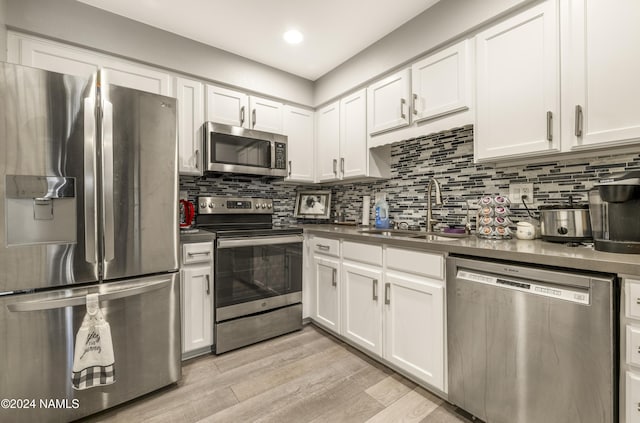 kitchen with sink, white cabinetry, light hardwood / wood-style flooring, and appliances with stainless steel finishes