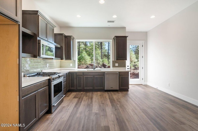 kitchen featuring appliances with stainless steel finishes, wood-type flooring, tasteful backsplash, sink, and dark brown cabinets