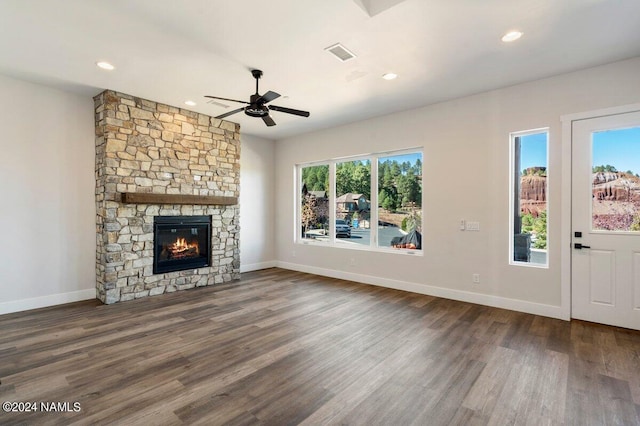 unfurnished living room with ceiling fan, dark hardwood / wood-style floors, and a stone fireplace