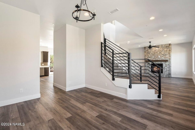 stairs featuring ceiling fan with notable chandelier, wood-type flooring, and a fireplace