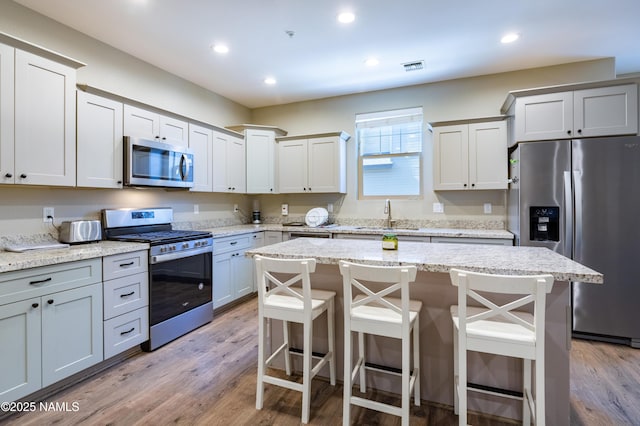 2553 W Cripple Creek Dr, Flagstaff, AZ 86001 - kitchen with stainless steel appliances, a sink, a breakfast bar area, light wood finished floors, and recessed lighting