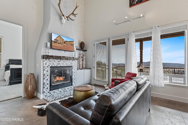 living room with a towering ceiling and a tiled fireplace