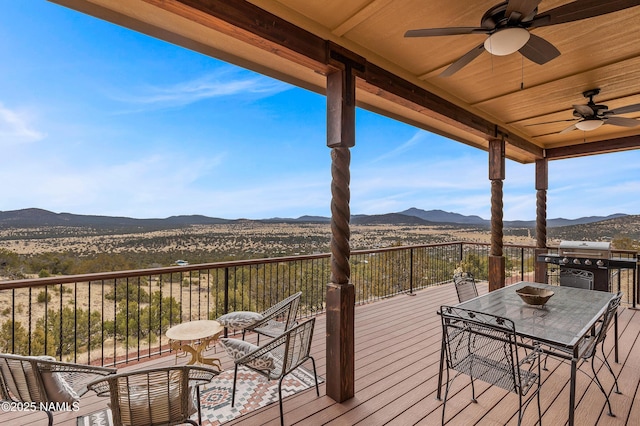 wooden terrace with ceiling fan, a mountain view, and grilling area