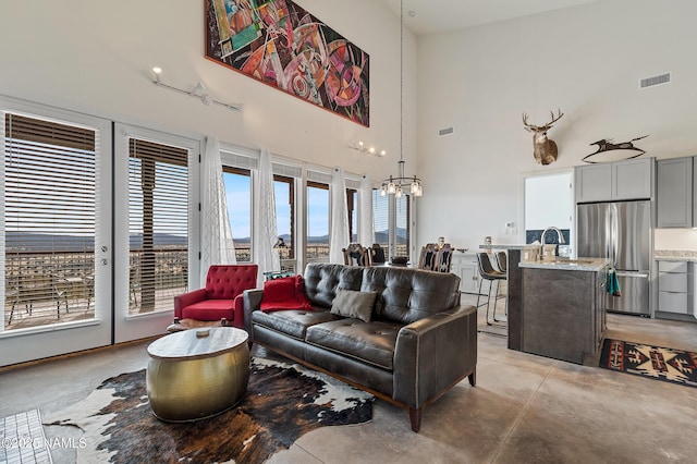 living room featuring sink, a chandelier, and a high ceiling