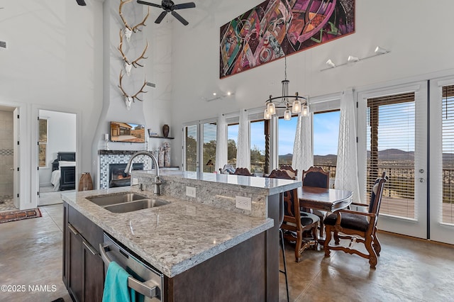 kitchen with dishwasher, sink, a high ceiling, dark brown cabinetry, and a center island with sink