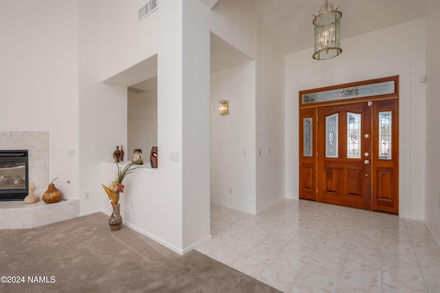 foyer featuring a chandelier, light colored carpet, and a premium fireplace