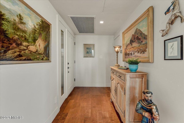 hallway featuring baseboards, wood finished floors, and visible vents