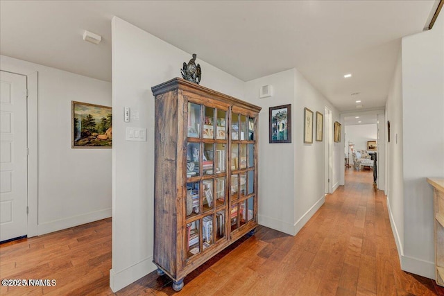hall featuring recessed lighting, baseboards, and light wood-type flooring