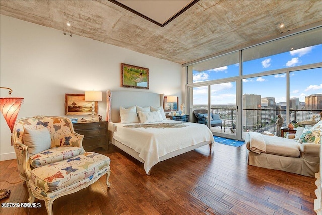 bedroom with a view of city, floor to ceiling windows, wood-type flooring, and access to outside