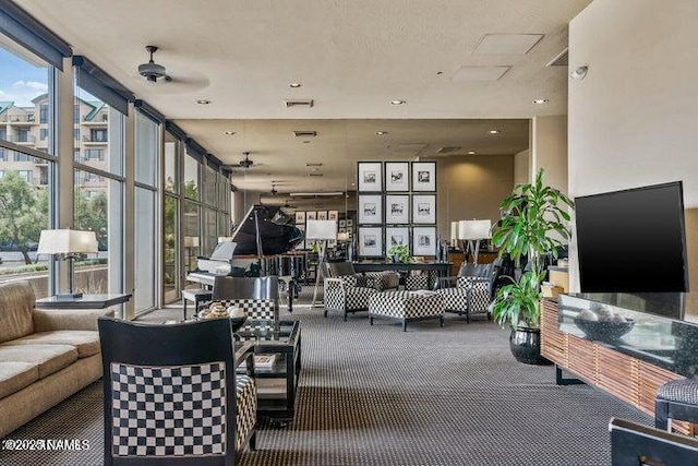 carpeted living room with visible vents, a ceiling fan, a healthy amount of sunlight, and expansive windows