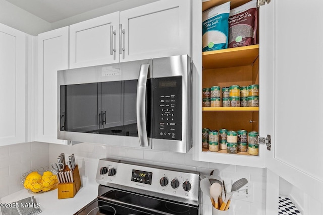 interior space featuring decorative backsplash, white cabinets, and appliances with stainless steel finishes