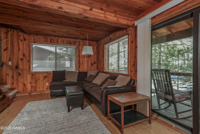 living room with wood walls, vaulted ceiling, wooden ceiling, and wood finished floors