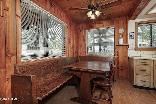 dining space with wooden walls, wood ceiling, and ceiling fan