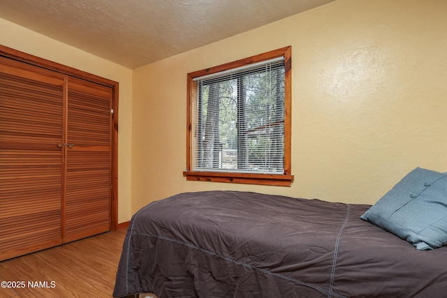 bedroom featuring a closet, a textured wall, wood finished floors, and a textured ceiling