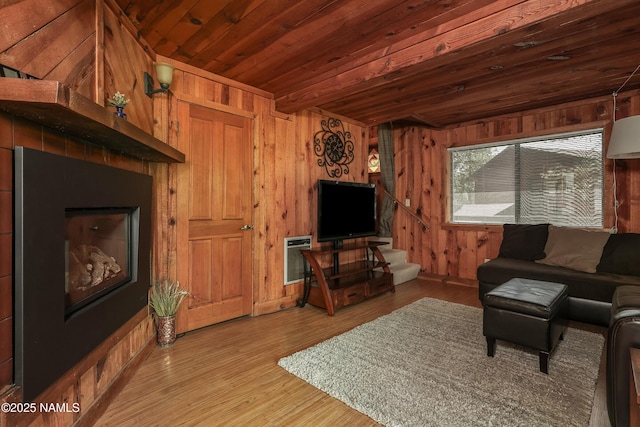 living area with wooden walls, wood ceiling, heating unit, and wood finished floors