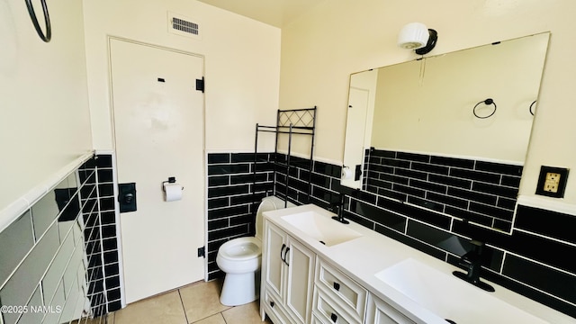 401 N Kinsley Ave, Winslow, AZ 86047 - bathroom featuring tile walls, tile patterned floors, a wainscoted wall, toilet, and double vanity